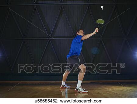 Young man playing badminton on court View Large Photo Image Stock Image - Young man playing badminton on court. Fotosearch