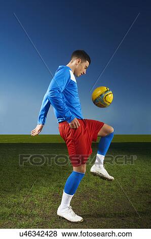 Stock Photo - Young man playing keepy uppy with football. Fotosearch