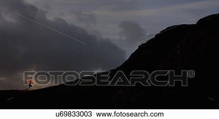 Young man running up silhouetted mountain View Large Photo Image Stock Image - Young man running up silhouetted mountain. Fotosearch