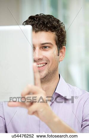 Young man self-photographing with digital tablet View Large Photo Image Stock Image - Young man self-photographing with digital tablet. Fotosearch