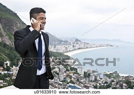Stock Image - Young man using mobile phone, Casa Alto Vidigal, Rio De Janeiro, Brazil. Fotosearch