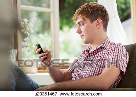 Young man using smartphone View Large Photo Image Stock Photo - Young man using smartphone. Fotosearch