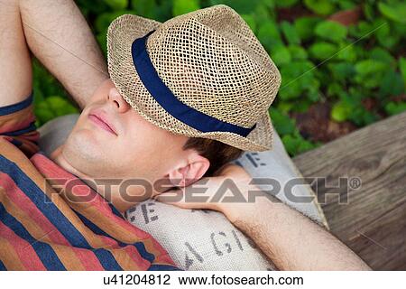 Young man wearing straw hat with hands behind head View Large Photo Image Stock Image - Young man wearing straw hat with hands behind head. Fotosearch