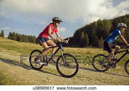 Stock Photo - Young woman and man mountain biking, Styria, Austria. Fotosearch