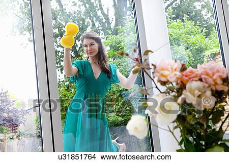 Picture - Young woman cleaning patio door. Fotosearch