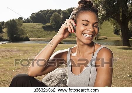 Young woman enjoying music in park View Large Photo Image Stock Image - Young woman enjoying music in park. Fotosearch