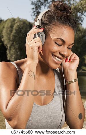 Young woman enjoying music on her headphones View Large Photo Image Stock Image - Young woman enjoying music on her headphones. Fotosearch