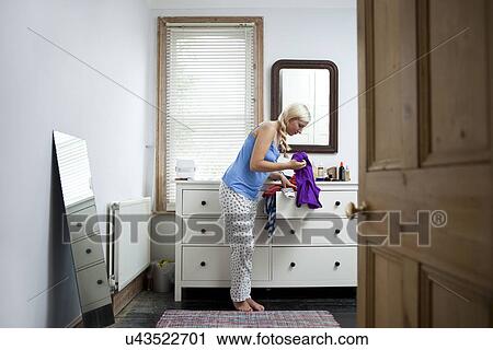Young woman in bedroom deciding on outfit View Large Photo Image Stock Image - Young woman in bedroom deciding on outfit. Fotosearch