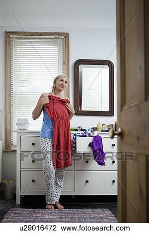 Stock Image - Young woman in bedroom getting ready. Fotosearch