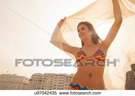 Young woman in bikini holding up sheer fabric View Large Photo Image Stock Photography - Young woman in bikini holding up sheer fabric. Fotosearch