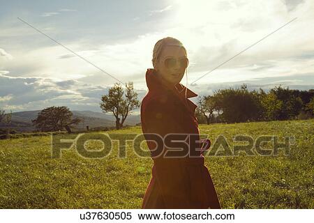 Stock Photography - Young woman in field posing in sunglasses. Fotosearch