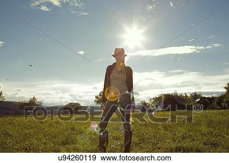 Young woman in field with blown bubbles View Large Photo Image Stock Photo - Young woman in field with blown bubbles. Fotosearch