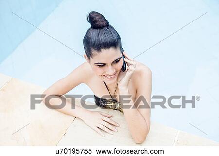 Young woman in swimming pool using mobile phone View Large Photo Image Stock Photography - Young woman in swimming pool using mobile phone. Fotosearch