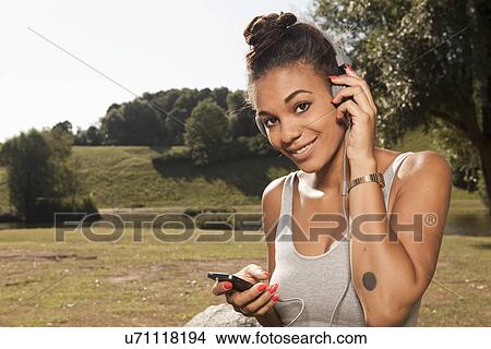 Young woman listening to mp3 player in park View Large Photo Image Picture - Young woman listening to mp3 player in park. Fotosearch