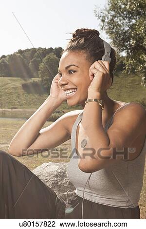 Young woman listening to music in park View Large Photo Image Stock Image - Young woman listening to music in park. Fotosearch