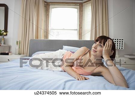 Young woman lying on bed daydreaming View Large Photo Image Stock Photography - Young woman lying on bed daydreaming. Fotosearch
