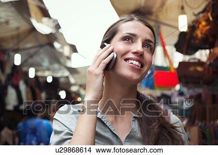 Picture - Young woman on cell phone, San Lorenzo market, Florence, Tuscany, Italy. Fotosearch
