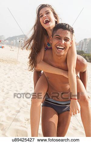 Young woman riding piggyback on man on beach View Large Photo Image Stock Photo - Young woman riding piggyback on man on beach. Fotosearch