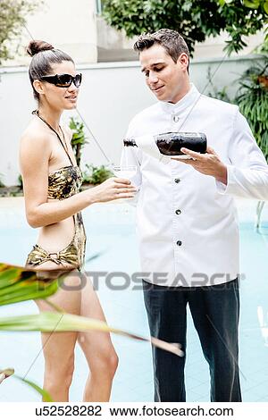 Stock Image - Young woman served champagne at hotel pool. Fotosearch