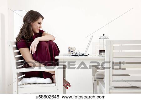 Young woman sitting at table with laptop View Large Photo Image Stock Photography - Young woman sitting at table with laptop. Fotosearch