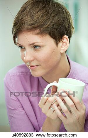 Stock Image - Young woman taking coffee break. Fotosearch
