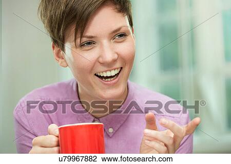 Stock Image - Young woman taking coffee break. Fotosearch