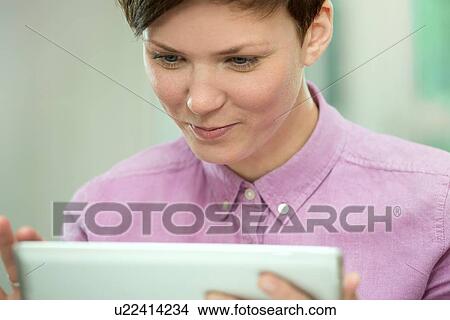 Picture - Young woman using digital tablet. Fotosearch
