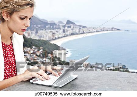 Stock Photography - Young woman using laptop, Casa Alto Vidigal, Rio De Janeiro, Brazil. Fotosearch