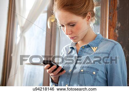 Stock Photograph - Young woman using smartphone. Fotosearch