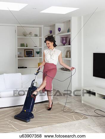 Young woman using vacuum cleaner in living room View Large Photo Image Stock Photo - Young woman using vacuum cleaner in living room. Fotosearch