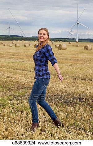 Young woman walking in harvested field View Large Photo Image Picture - Young woman walking in harvested field. Fotosearch