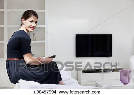 Picture - Young woman wearing black dress in living room. Fotosearch