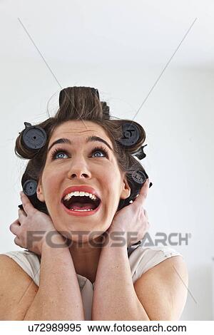 Stock Photography - Young woman wearing hair rollers looking up. Fotosearch