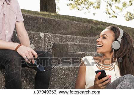 Young woman wearing headphones, looking at young man View Large Photo Image Stock Image - Young woman wearing headphones, looking at young man. Fotosearch