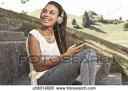 Stock Photo - Young woman wearing headphones, looking over shoulder. Fotosearch
