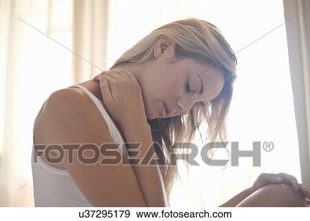 Young woman with head down and hand on neck View Large Photo Image Stock Photo - Young woman with head down and hand on neck. Fotosearch