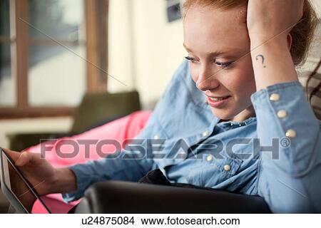 Picture - Young woman with question mark tattoo using digital tablet. Fotosearch