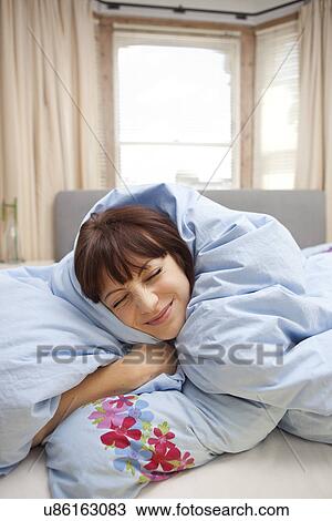 Young woman wrapped in duvet View Large Photo Image Stock Image - Young woman wrapped in duvet. Fotosearch