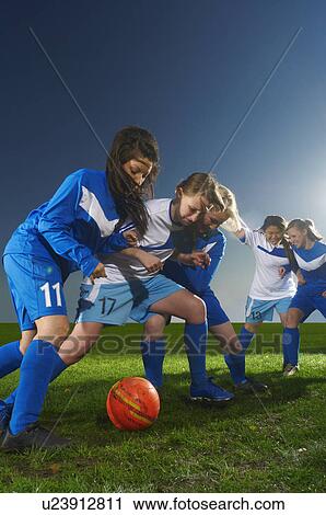 Stock Image - Young women playing football. Fotosearch