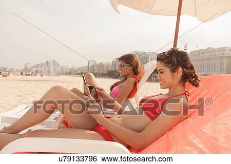 Young women using digital tablet on beach View Large Photo Image Stock Photograph - Young women using digital tablet on beach. Fotosearch
