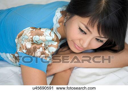 Stock Image - Greenery, Young Couple, Lying Down, Leisure Activity, Young Adult, Asian Ethnicity. Fotosearch