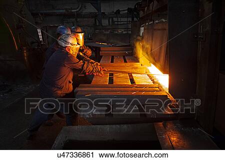 Stock Image - 100mm square steel billet is removed from furnace as cold steel billet waits in foreground to be heated. Fotosearch