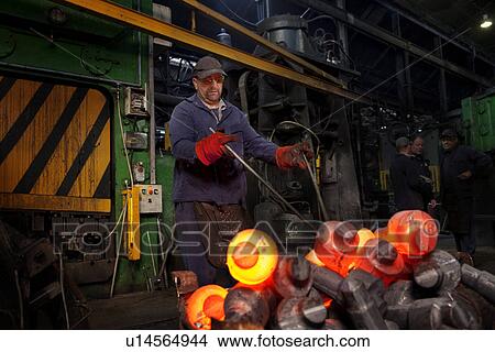 A clipped crank shaft is swung out in a pair of tongs from the clipping press into a steel container View Large Photo Image Picture - A clipped crank shaft is swung out in a pair of tongs from the clipping press into a steel container. Fotosearch
