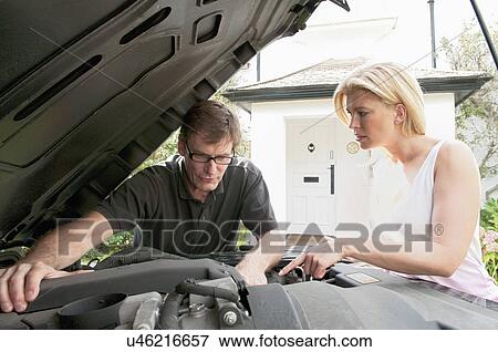 Stock Photo - Adult couple checking under car hood. Fotosearch