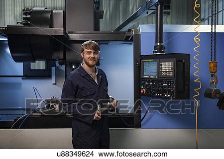 Apprentice holding a u-bolt strap in front of CNC machine View Large Photo Image Picture - Apprentice holding a u-bolt strap in front of CNC machine. Fotosearch