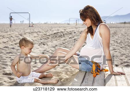Baby on beach tipping sand onto mother's hand View Large Photo Image Stock Photo - Baby on beach tipping sand onto mother's hand. Fotosearch
