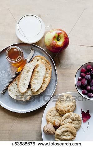 Stock Photograph - Baquette with honey, cookies, milk and fruits. Fotosearch