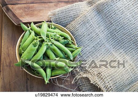 Picture - Bowl of peapods on table with burlap. Fotosearch