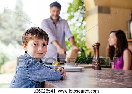 Boy at table with father and sister in background View Large Photo Image Stock Image - Boy at table with father and sister in background. Fotosearch