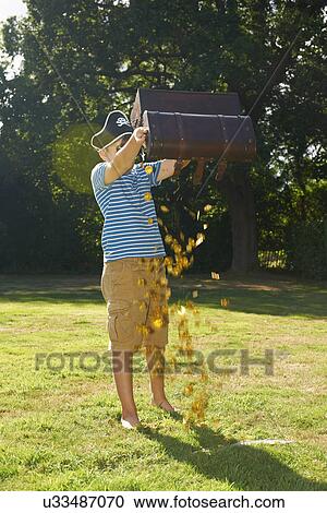 Boy dressed as pirate emptying gold from treasure chest in garden View Large Photo Image Stock Image - Boy dressed as pirate emptying gold from treasure chest in garden. Fotosearch